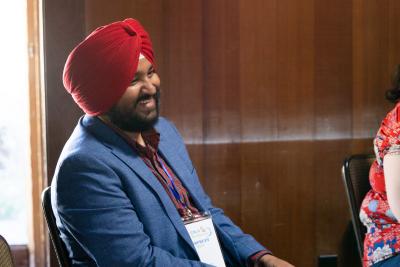 smiling man wearing blue suit coat and red pagri