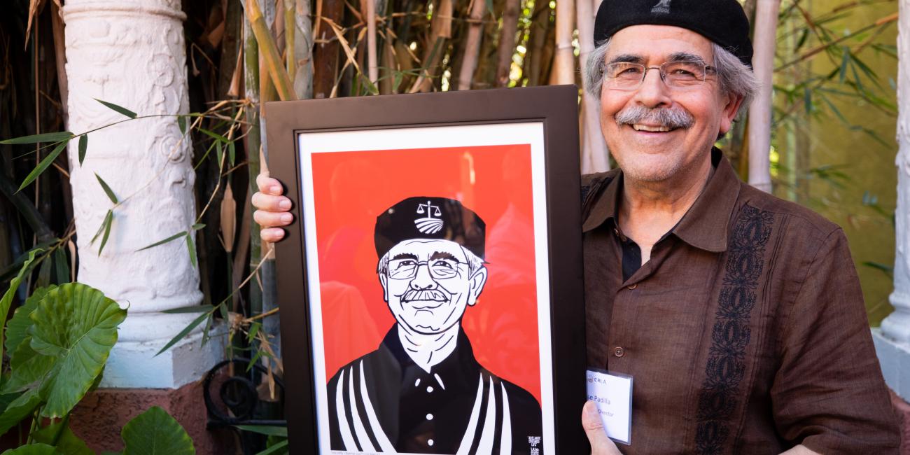 CRLA Executive Director Jose Padilla holds portrait created by Lalo Alcaraz September 2022
