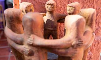 clay sculpture of people embracing in a circle