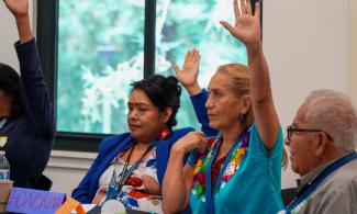 CRLA board members raise hands while seated at conference table