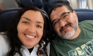 Selfie photo of two people smiling while seated on an airplane